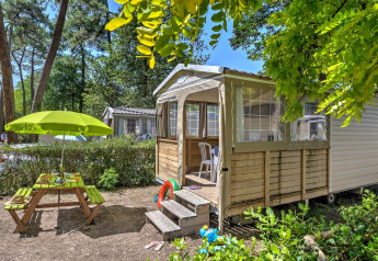 Safari-Zelt Cabane Nature bei Flower Camping Au Bois Des Biches, mit Picknicktisch und Sonnenschirm in Frankreich.