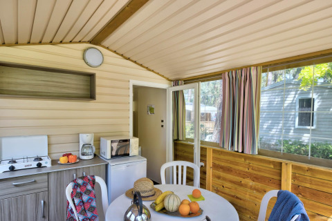 Indvendigt billede af Cabane Nature safari-telt med spisebord, køkkenudstyr, og farverige gardiner.