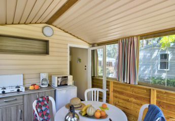 Innenaufnahme des Cabane Nature Safari-Zelts mit Esstisch, Küchenutensilien und bunten Vorhängen.