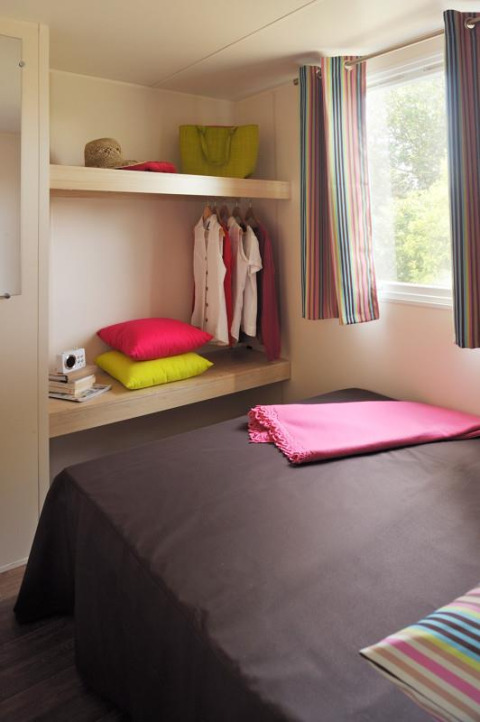 Camera da letto nella tenda safari Cabane Nature al Flower Camping Au Bois Des Biches, Francia, con decori colorati.