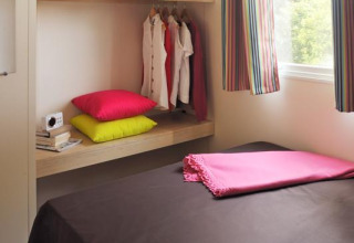 Schlafzimmer im Safari-Zelt Cabane Nature bei Flower Camping Au Bois Des Biches in Frankreich mit bunten Vorhängen.