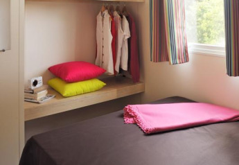 Camera da letto nella tenda safari Cabane Nature al Flower Camping Au Bois Des Biches, Francia, con decori colorati.