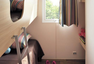 Kinderzimmer in einem Safari-Zelt Cabane Nature mit Etagenbett, Fenster, bunten Kissen und Holzboden.