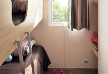 Kinderzimmer in einem Safari-Zelt Cabane Nature mit Etagenbett, Fenster, bunten Kissen und Holzboden.