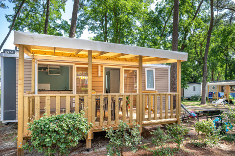 Træchalet Stacaravan Confort på Flower Camping Au Bois Des Biches, omgivet af grønne træer i Frankrig.