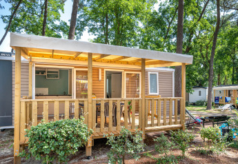 Stacaravan Confort chalet at Flower Camping Au Bois Des Biches, France, with wooden porch in a forest setting.