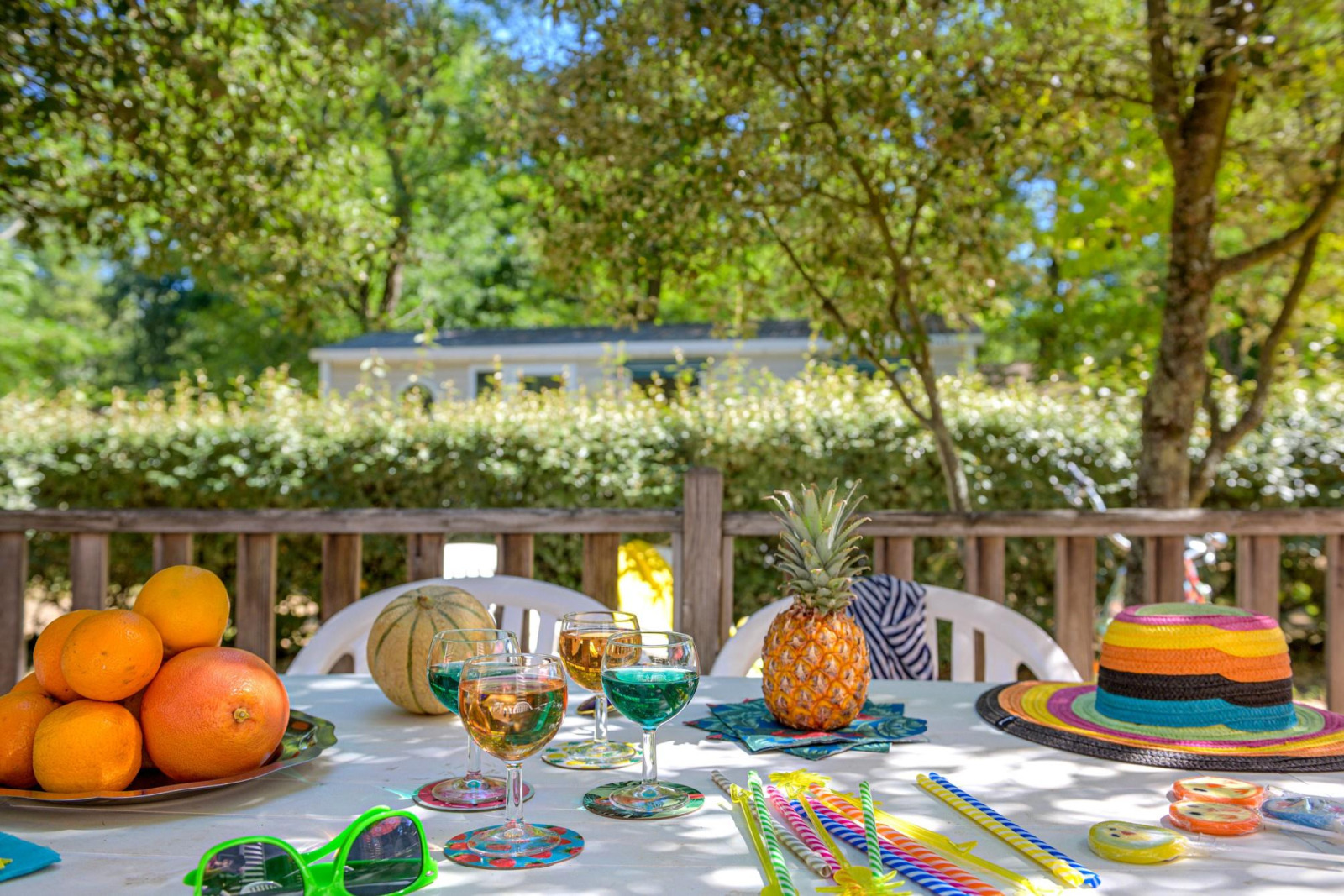 Buitentafel met fruit, drankjes en hoed bij Stacaravan Confort, Flower Camping Au Bois Des Biches, Frankrijk.