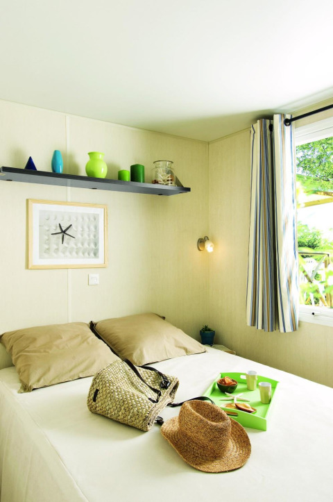Lichte en gezellige slaapkamer in Stacaravan Confort van Flower Camping Au Bois Des Biches, Frankrijk, met venster.