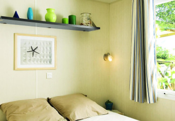Helles Schlafzimmer im Stacaravan Confort bei Flower Camping Au Bois Des Biches mit Tablett und Fenster.