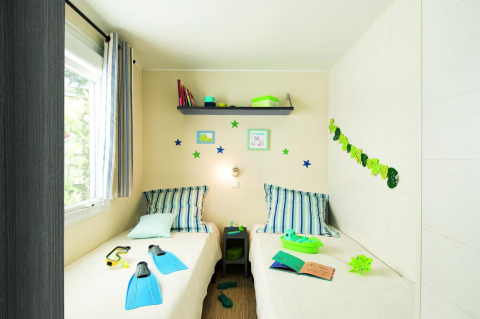 Helles Chalet-Schlafzimmer mit zwei Einzelbetten, Deko und Fenstern im Flower Camping Au Bois Des Biches.