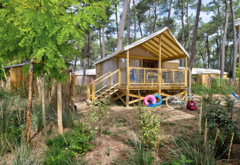 Accogliente casa sull'albero Cosyflower in una foresta, con veranda, bici e salvagenti colorati davanti.