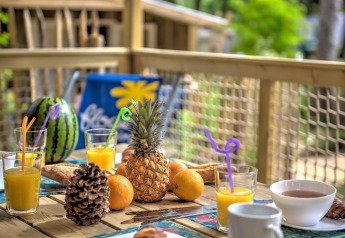 Morgenmad på træhusets terrasse med frisk frugt, juice og kaffe i Cosyflower, Flower Camping Au Bois Des Biches.