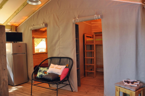 Interieur van boomhut Cosyflower bij Flower Camping Au Bois Des Biches, Frankrijk, met zitje en stapelbed.