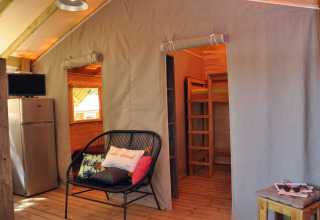 Interieur van boomhut Cosyflower bij Flower Camping Au Bois Des Biches, Frankrijk, met zitje en stapelbed.