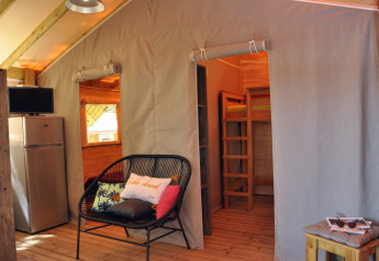 Indvendig billede af træhus Cosyflower med soveplads, køleskab og siddeområde på Flower Camping Au Bois Des Biches.