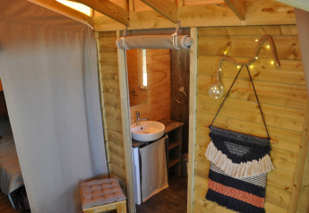 Interno di una casetta sull'albero accogliente con bagno e decorazioni a Flower Camping Au Bois Des Biches, Francia.