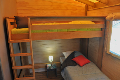 Chambre cabane en bois avec mezzanine et lit simple au Flower Camping Au Bois Des Biches en France.