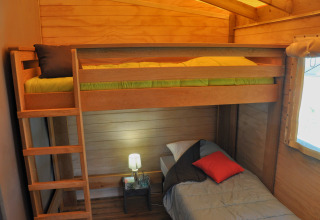 Chambre cabane en bois avec mezzanine et lit simple au Flower Camping Au Bois Des Biches en France.