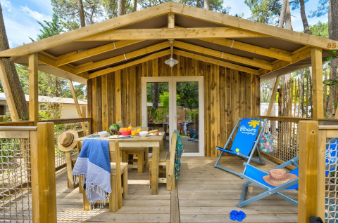 Gemütliche Sweetflower-Lodge auf Flower Camping Au Bois Des Biches in Frankreich mit Holzterrasse.