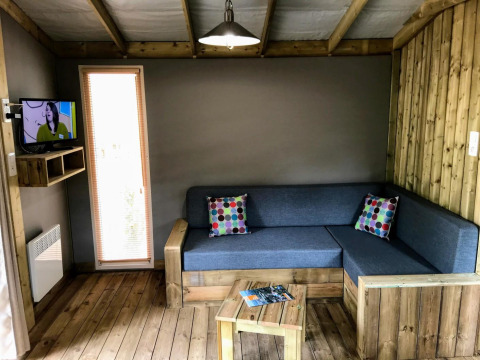 Woonkamer in Sweetflower lodge bij Flower Camping Au Bois Des Biches, Frankrijk, met houten vloer.