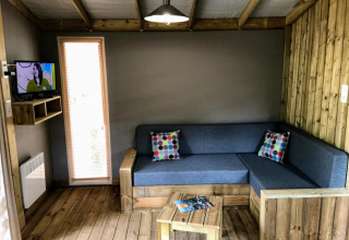 Wohnbereich der Sweetflower-Lodge im Flower Camping Au Bois Des Biches, Frankreich, mit Holzboden.