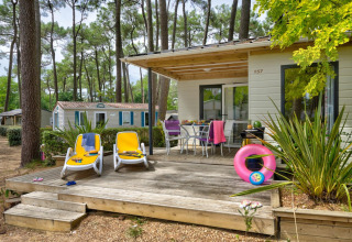 Terrazza all’aperto con lettini e tavolo al Cottage Premium di Flower Camping Au Bois Des Biches in Francia.