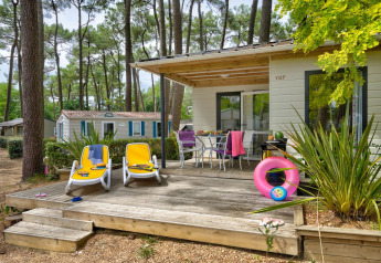 Udendørs terrasse med liggestole og bord foran Cottage Premium på Flower Camping Au Bois Des Biches i Frankrig.