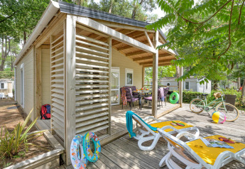 Buitenterras van Cottage Premium bij Flower Camping Au Bois Des Biches met ligstoelen, fiets en opblaasband.