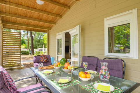 Veranda coperta del Cottage Premium al Flower Camping Au Bois Des Biches in Francia, tavolo apparecchiato e vista.