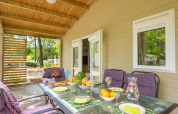 Terraza cubierta en Cottage Premium de Flower Camping Au Bois Des Biches, Francia, mesa puesta y vistas naturales.