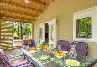Veranda coperta del Cottage Premium al Flower Camping Au Bois Des Biches in Francia, tavolo apparecchiato e vista.