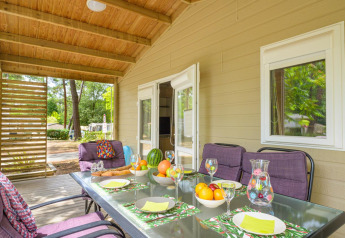 Overdekt terras aan Cottage Premium, Flower Camping Au Bois Des Biches, Frankrijk, met tafel en natuurzicht.