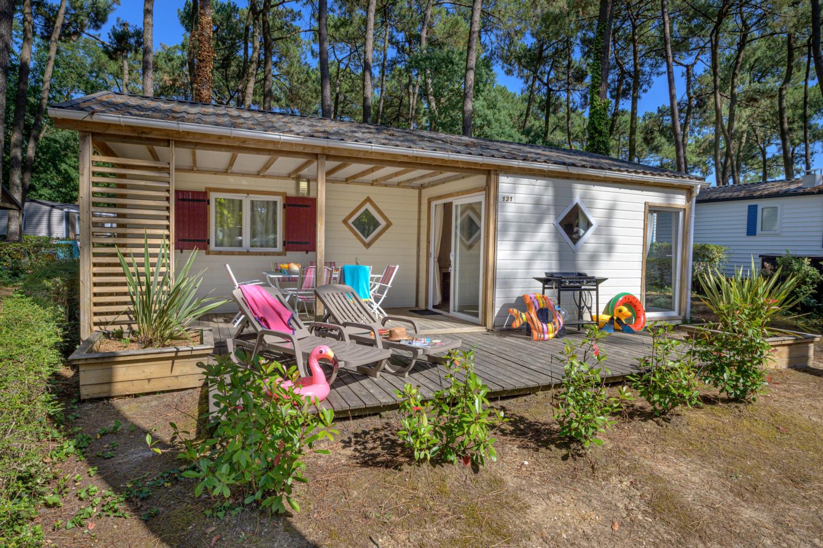 Premium houten cottage met terras en ligstoelen bij Flower Camping Au Bois Des Biches in Frankrijk.