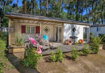 Træhytte med terrasse og havemøbler omgivet af skov på Flower Camping Au Bois Des Biches i Frankrig.