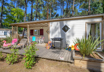 Terraza exterior en Cottage Premium en Flower Camping Au Bois Des Biches, Francia, con sillas y juguetes.