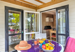Terrazza del Cottage Premium a Flower Camping Au Bois Des Biches con frutta, succhi e cappello di paglia sul tavolo.