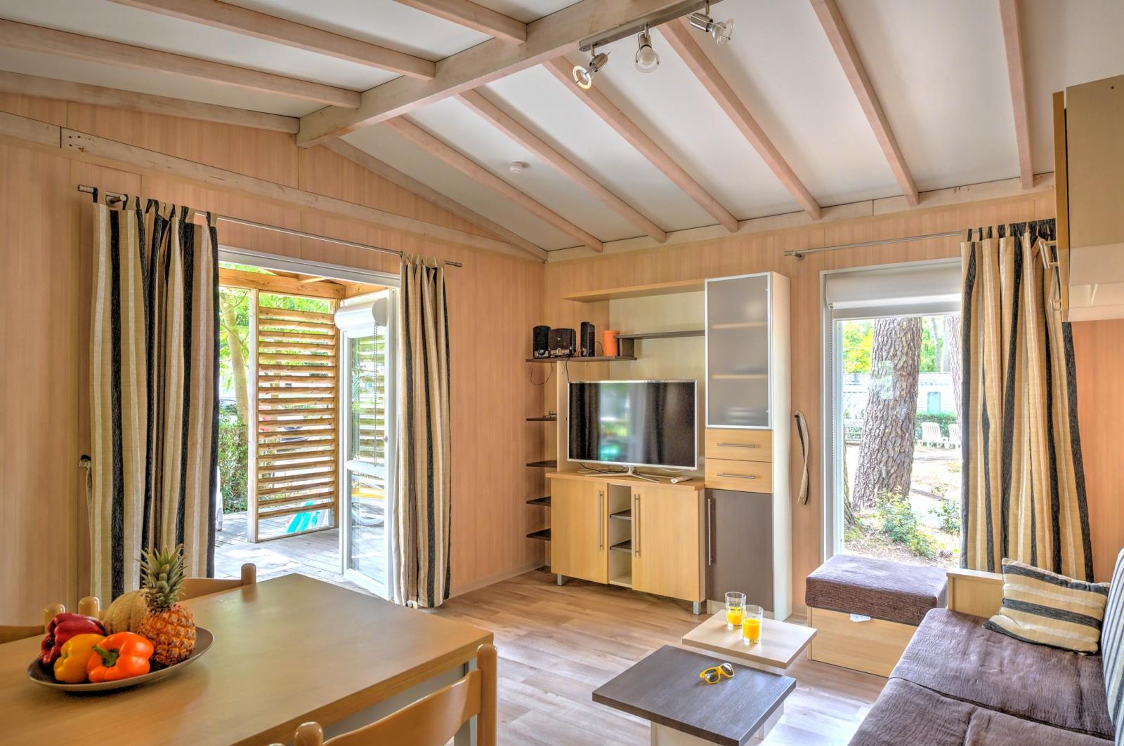 Lichte woonkamer in Cottage Premium bij Flower Camping Au Bois Des Biches, met moderne inrichting en grote ramen.