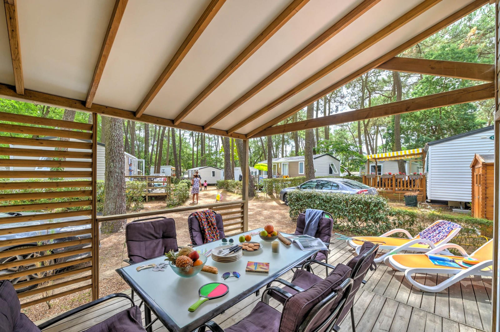 Overdekt terras bij Cottage Premium op Flower Camping Au Bois Des Biches in Frankrijk, met tafel en stoelen.