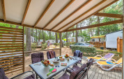 Terraza cubierta en Cottage Premium de Flower Camping Au Bois Des Biches en Francia, con mesa y tumbonas.