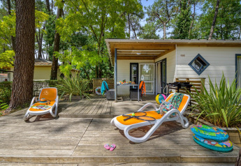 Terrazza soleggiata con lettini davanti al Cottage Premium presso Flower Camping Au Bois Des Biches in Francia.