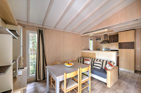 Stue og køkkenområde i Cottage Premium ved Flower Camping Au Bois Des Biches i Frankrig, lyst og hyggeligt.