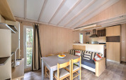 Stue og køkkenområde i Cottage Premium ved Flower Camping Au Bois Des Biches i Frankrig, lyst og hyggeligt.