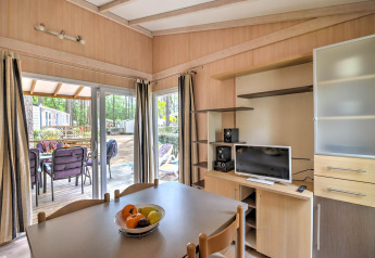 Sala con mesa de comedor, televisor y acceso a terraza en Cottage Premium en Flower Camping Au Bois Des Biches, Francia.