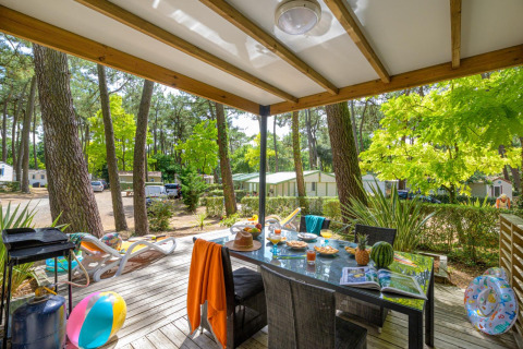 Udendørs terrasse ved Cottage Premium på Flower Camping Au Bois Des Biches i Frankrig, omgivet af skov.