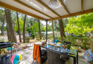 Udendørs terrasse ved Cottage Premium på Flower Camping Au Bois Des Biches i Frankrig, omgivet af skov.