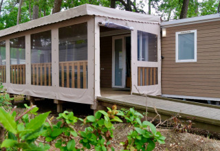 Chalet Stacaravan Life at Flower Camping Au Bois Des Biches, France, with covered terrace and wooded setting.