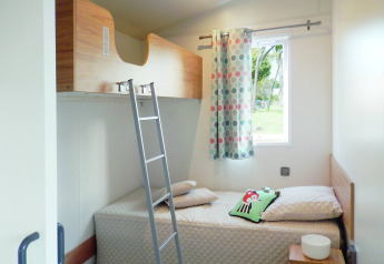 Helles Zimmer im Stacaravan Life bei Flower Camping Au Bois Des Biches mit Etagenbett und bunzem Vorhang.