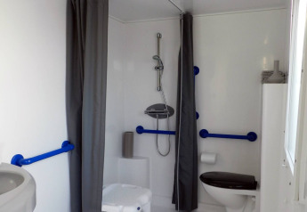 Baño accesible en Stacaravan Life en Flower Camping Au Bois Des Biches, con ducha, asiento y pasamanos.