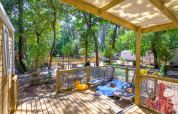 Terrasse ensoleillée de la Stacaravan Family au Flower Camping Au Bois Des Biches, entourée de verdure.