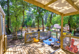Zonnig terras bij Stacaravan Family op Flower Camping Au Bois Des Biches, tussen de bomen en chaletjes.